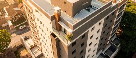 A multi-story building with a flat roof, large windows, and a rooftop garden.