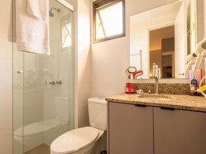 A bathroom with a glass-enclosed shower, a white toilet, a granite countertop, and a mirror. - Easy Life Campus PUC by Xtay (Curitiba)