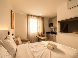 A hotel room with a bed, a desk, a chair, a microwave, and a TV. - Easy Life Campus PUC by Xtay (Curitiba)