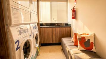 A compact laundry room with a washing machine, a dryer, and a small kitchenette.