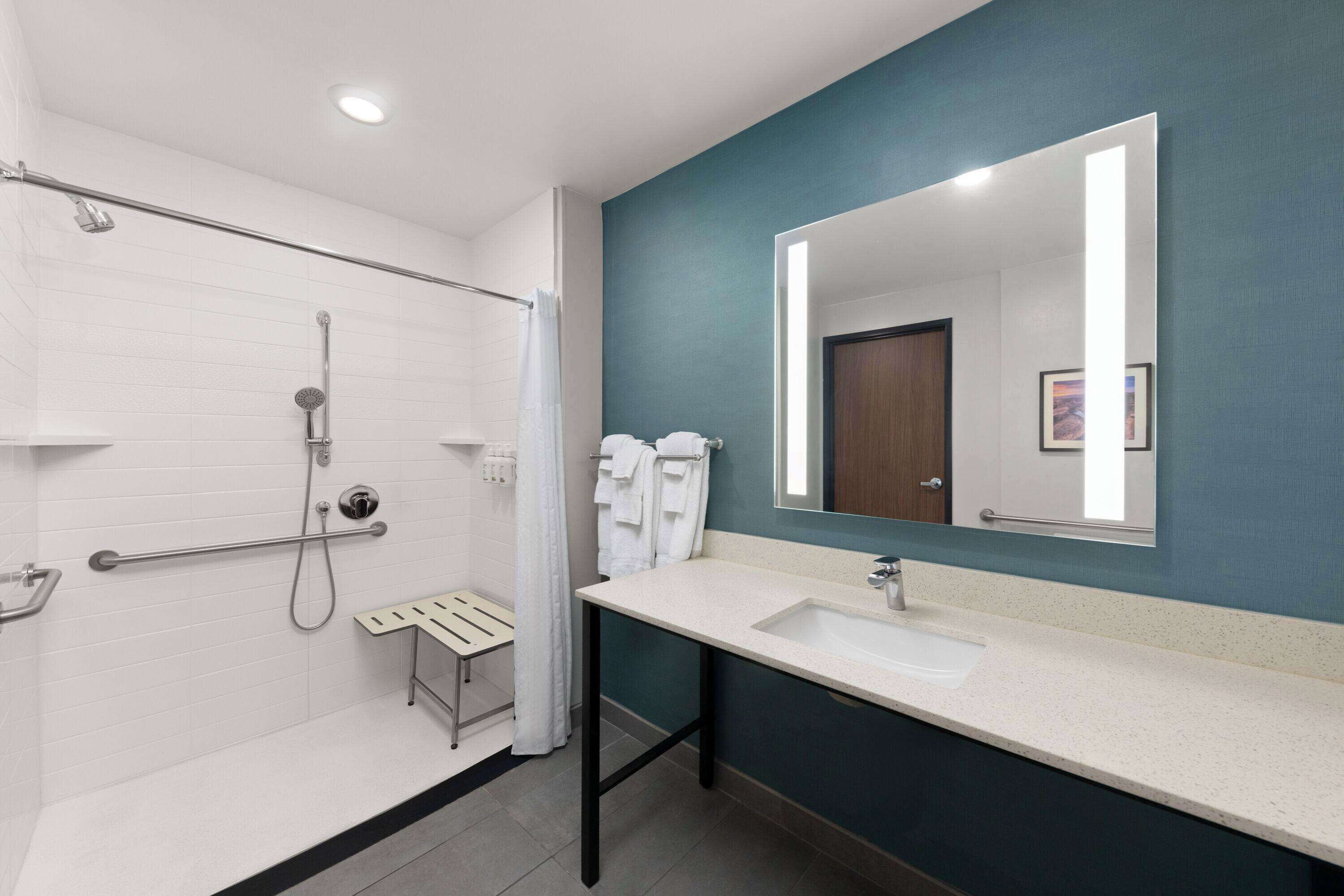 Un baño moderno con ducha blanca, lavamanos y espejo.