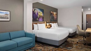 A hotel room with two beds, a sofa, a desk, and two paintings on the wall. - La Quinta Inn & Suites By Wyndham Yuma (Yuma)