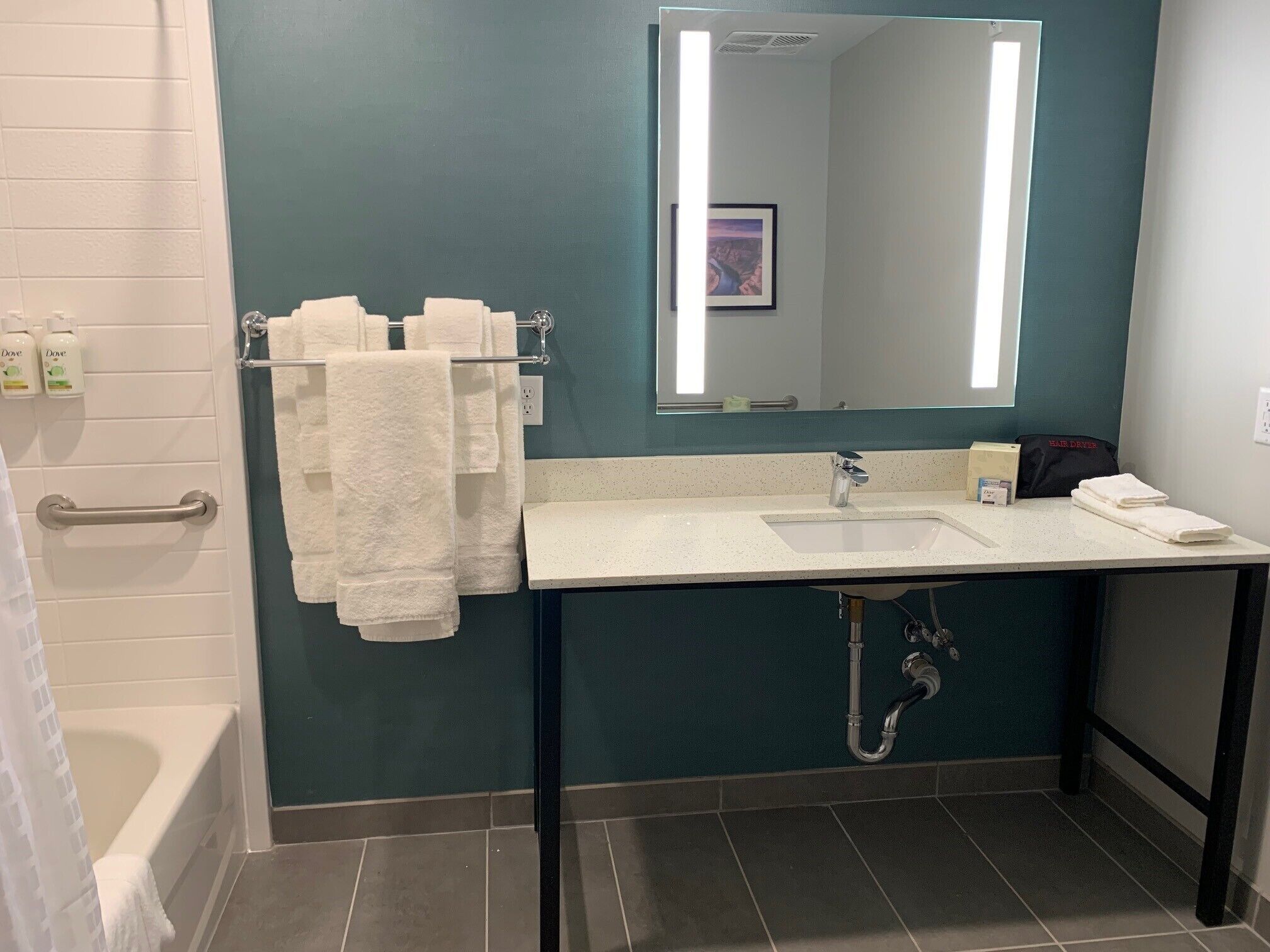 A bathroom with a bathtub, a sink with a mirror, and a towel rack.