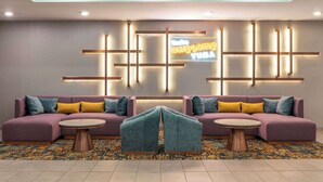 A modern lobby with a sectional sofa, two round tables, and a neon sign. - La Quinta Inn & Suites By Wyndham Yuma (Yuma)