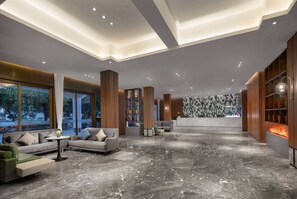 Een moderne lobby met een marmeren vloer, banken, een receptiebalie en een boekenplank.