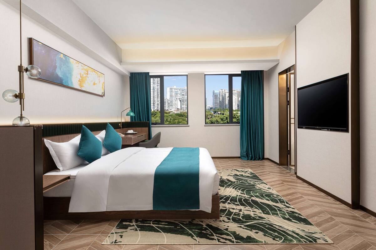 Une chambre d’hôtel moderne dotée d’un grand lit, d’une télévision à écran plat, d’un bureau et offrant une vue sur la ville.