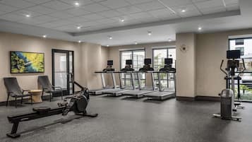 A gym with treadmills, a rowing machine, and exercise chairs.