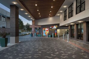 An outdoor area with a patterned floor, a brick pillar, and a colorful mural. - Hampton Inn by Hilton Austin East Side 5th Street (Austin)