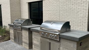 Un mur extérieur en briques avec deux barbecues en acier inoxydable.