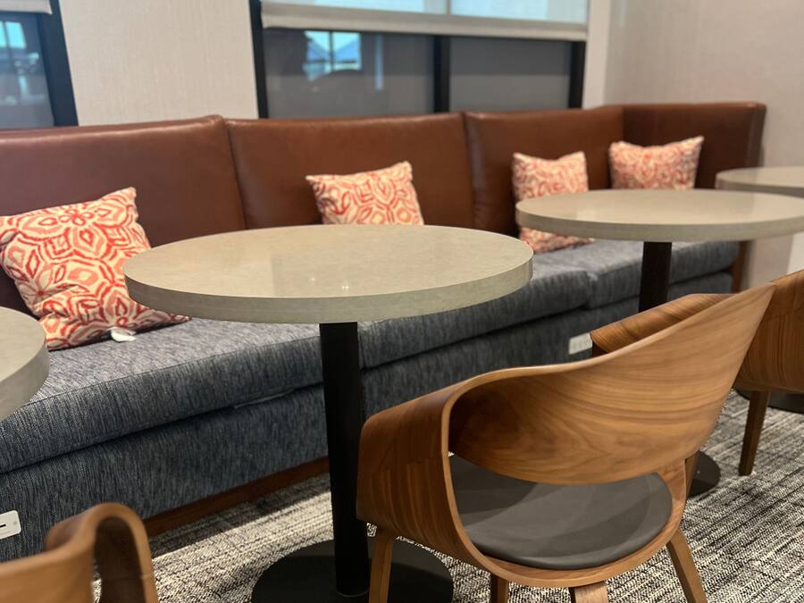 A seating area with a sofa and two round tables, a wooden chair, and patterned cushions.