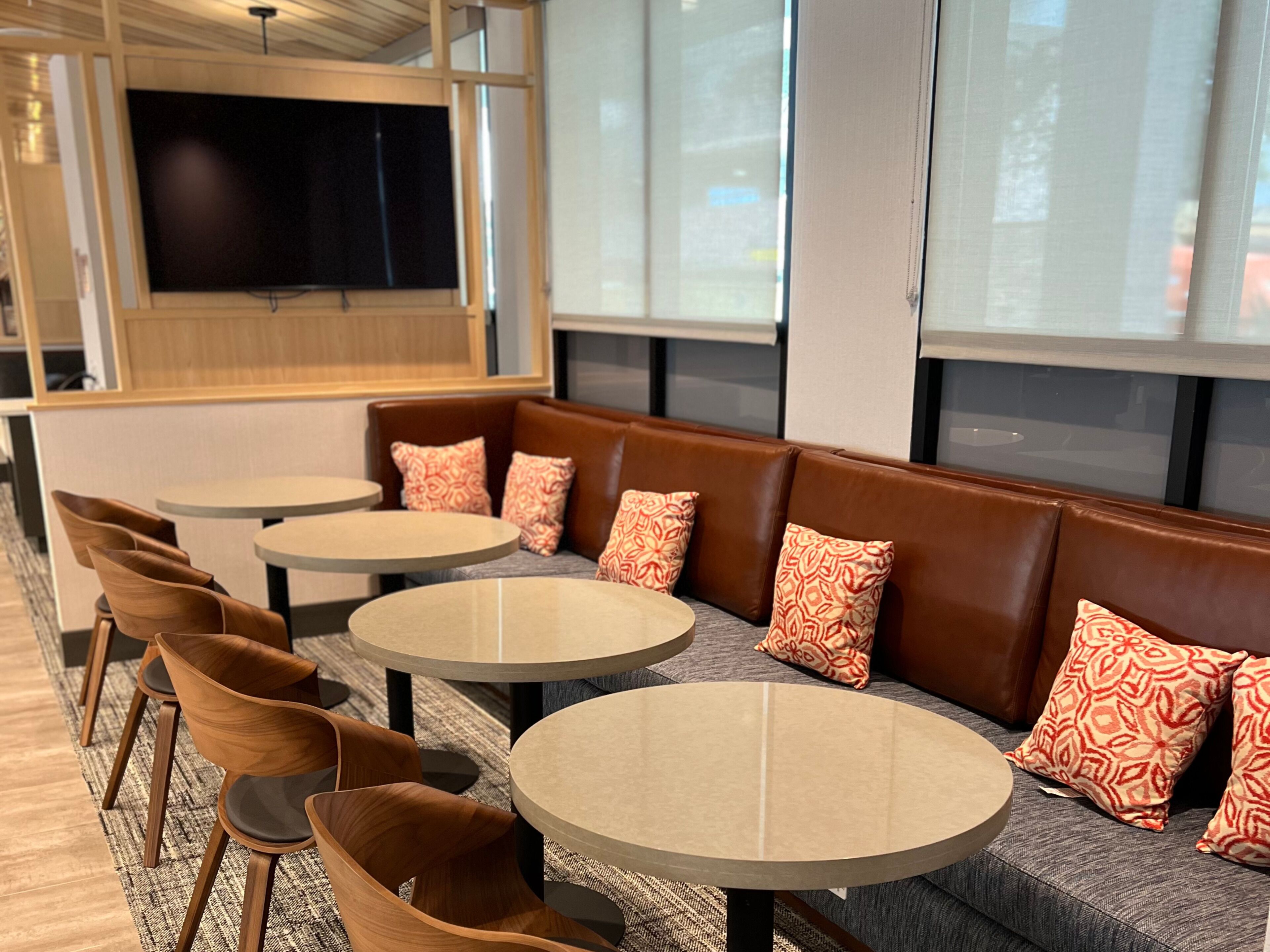 A modern seating area with round tables and leather sofas, featuring patterned cushions.