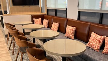 A modern seating area with round tables and leather sofas, featuring patterned cushions.