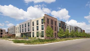 Un immeuble moderne à plusieurs étages, avec une façade combinant briques et verre, de grandes fenêtres et un toit plat.