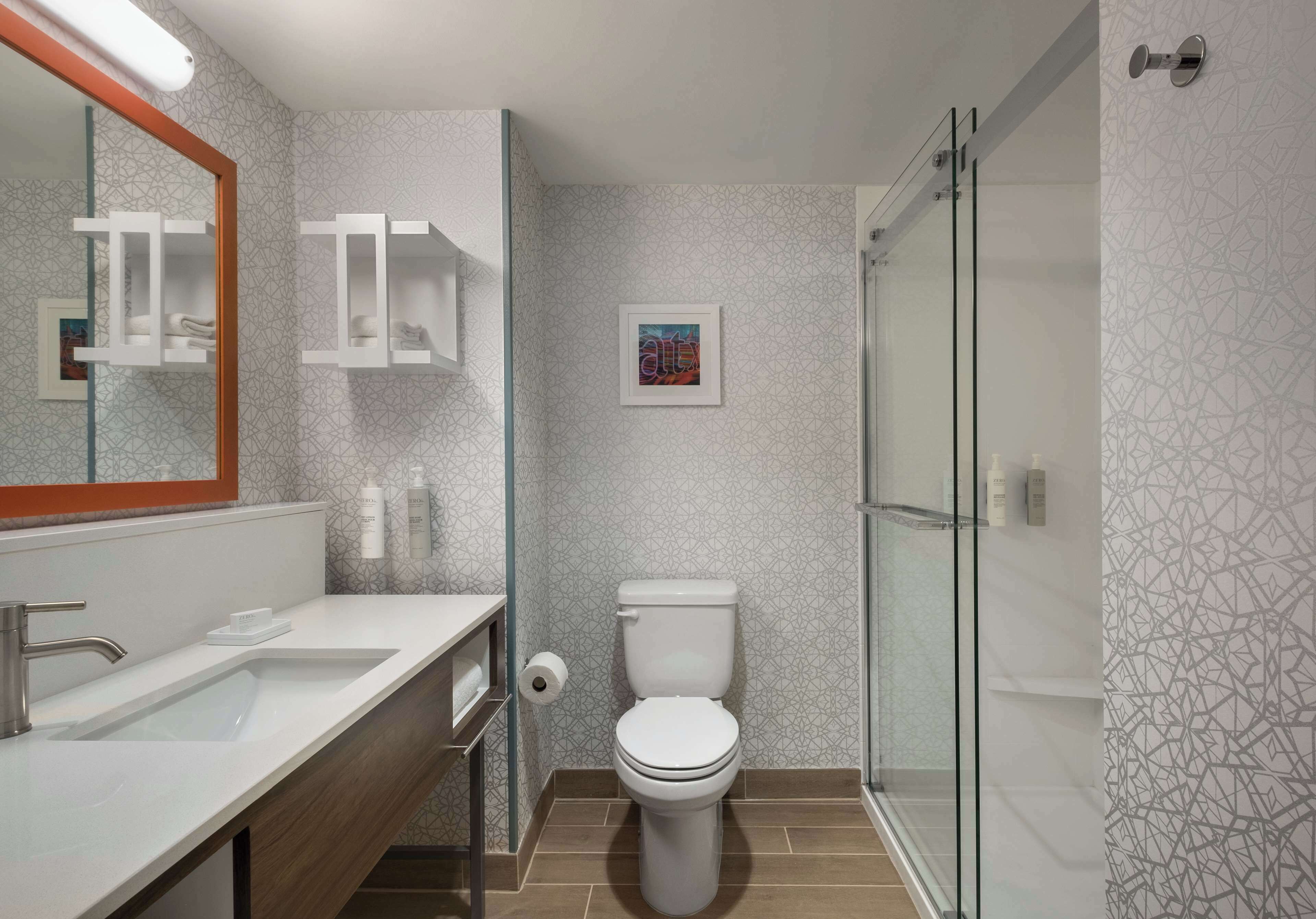 A modern bathroom with a white sink, a toilet, and a glass shower enclosure.