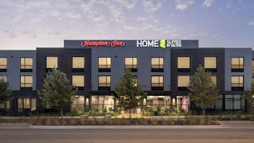 A hotel with a modern design, featuring a prominent sign for Hampton Inn and Home 2 Suites by Hilton.