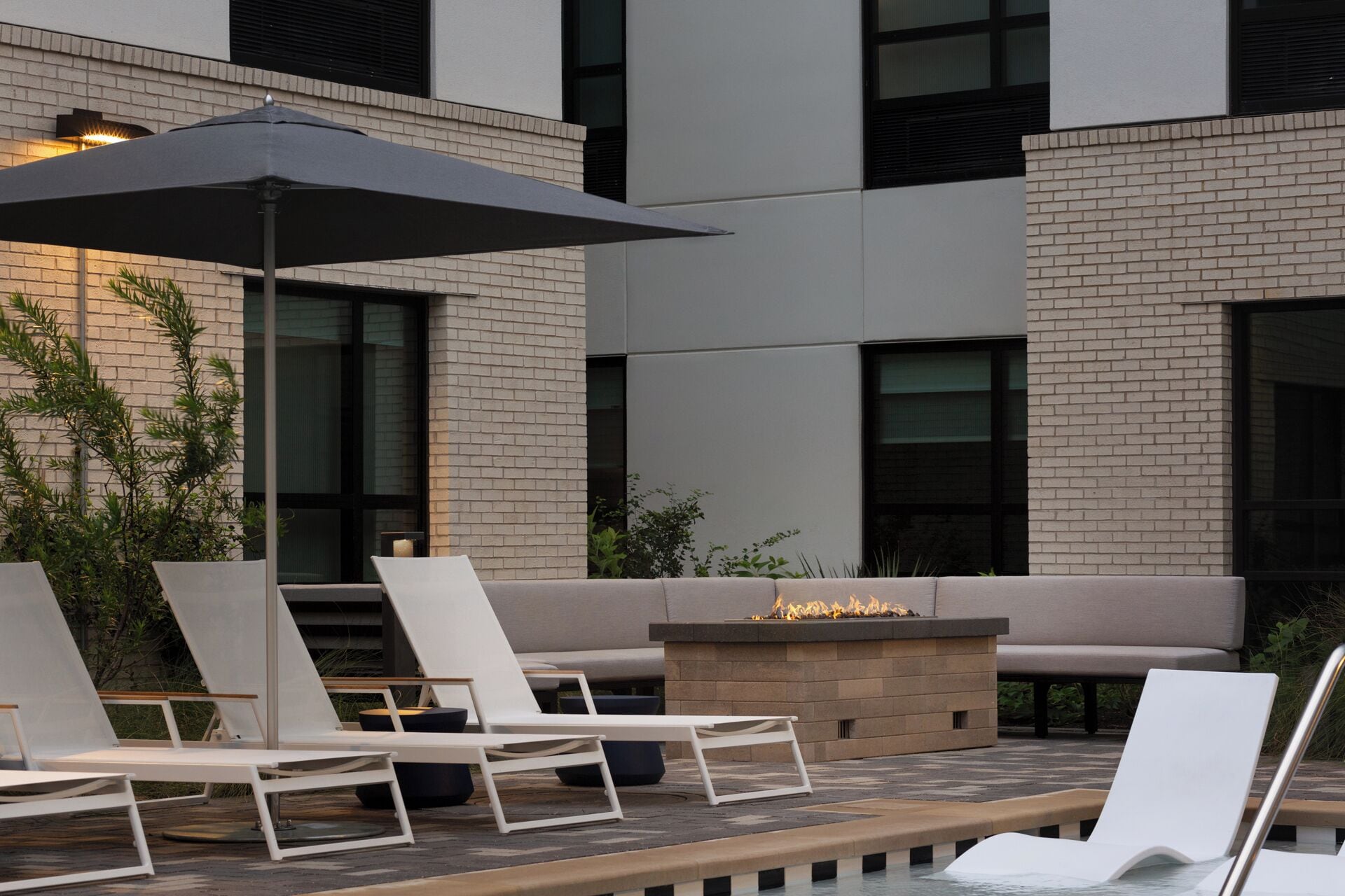 Un espacio de esparcimiento moderno al aire libre con sillones de descanso y una chimenea.