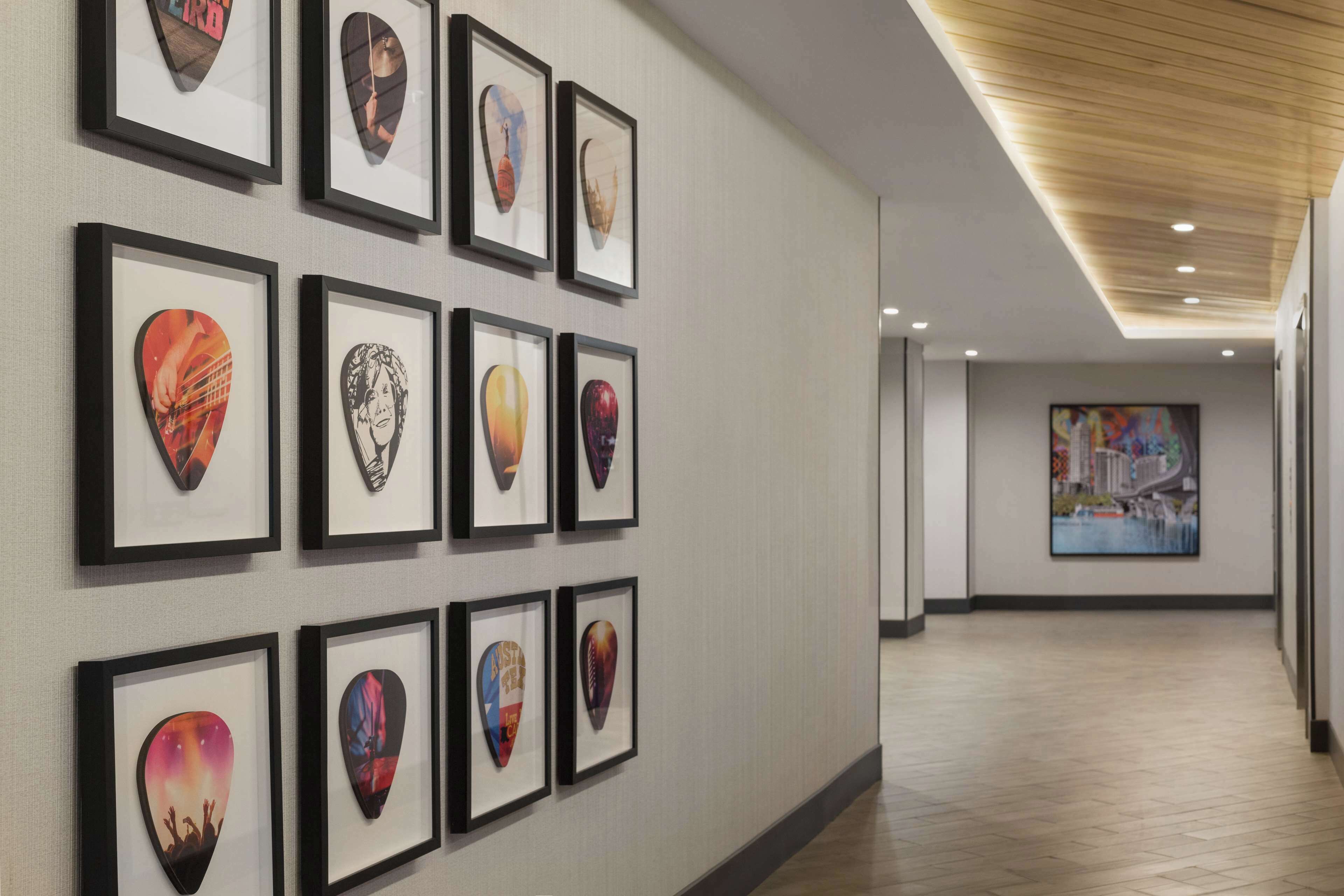 A hallway with framed guitar picks on the wall and a large painting in the distance.