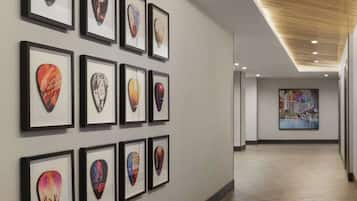 A hallway with framed guitar picks on the wall and a large painting in the distance.