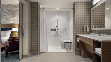 Un baño de hotel moderno con ducha, tocador y un espejo grande.
