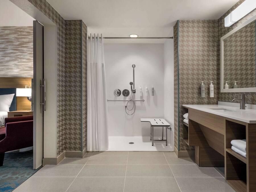 Un baño de hotel moderno con ducha, tocador y un espejo grande.