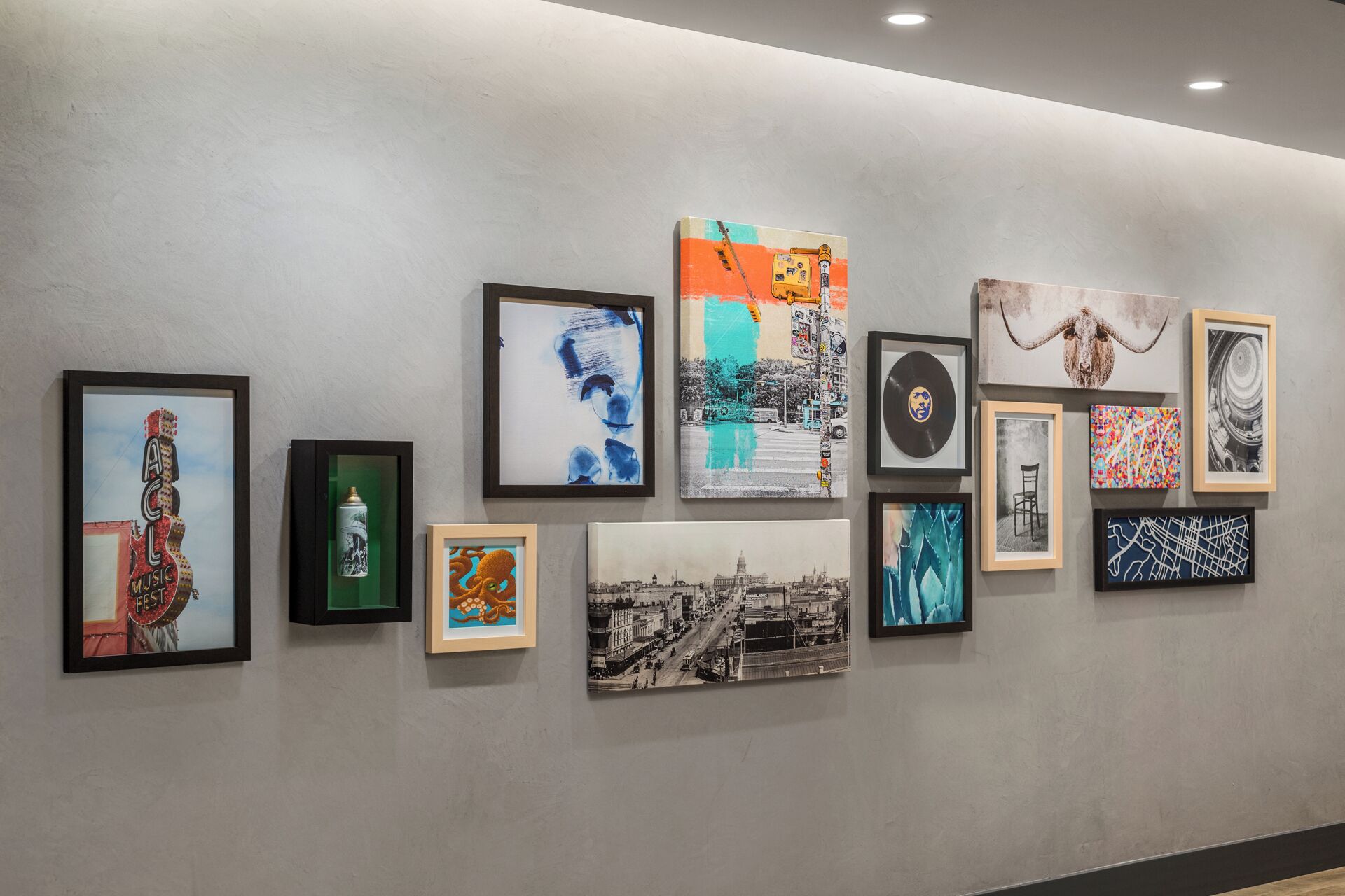 Una galería de cuadros con diversas obras de arte enmarcadas, incluyendo pinturas y fotografías.