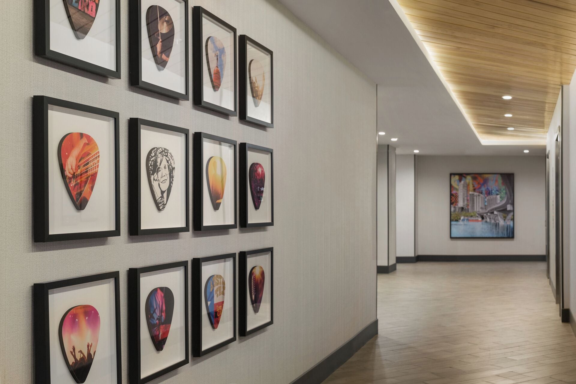 A hallway with framed artwork on the walls and a large painting on the far wall.
