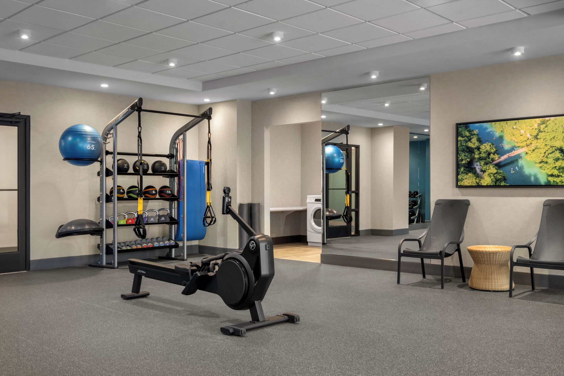 Ein Fitnessraum mit Trainingsgeräten, einer Sitzecke und einem großen Fenster mit Blick.
