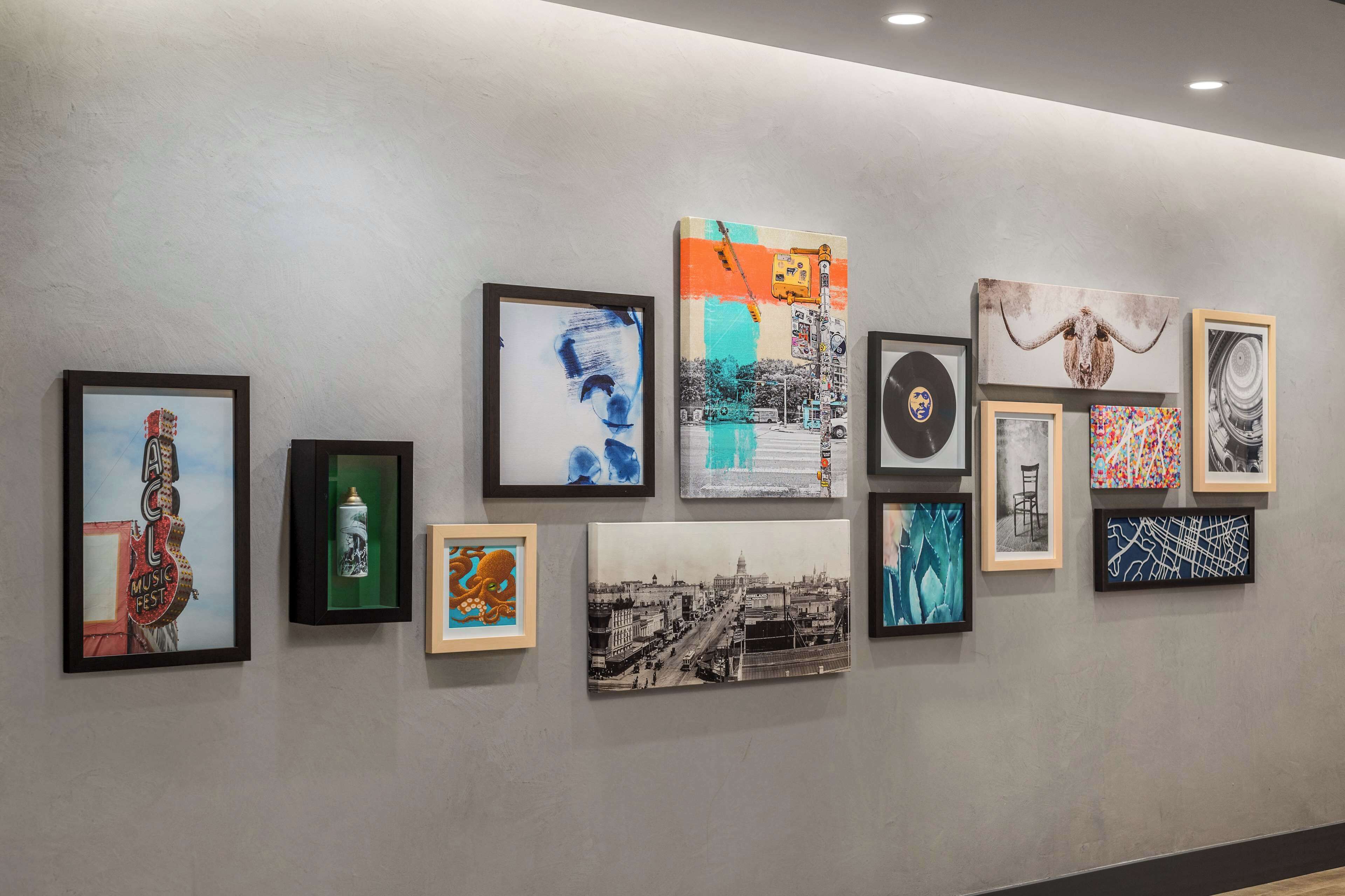 A gallery wall with various framed artworks including abstract paintings, a vintage photograph, and a sculpture.