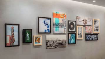 A gallery wall with various framed artworks including abstract paintings, a vintage photograph, and a sculpture.