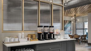 Una estación de café con varios dispensadores, una máquina de café y una variedad de tazas y vasos.