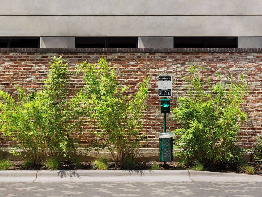 A brick wall with a green trash can and a recycling bin, and a sign indicating a parking area.