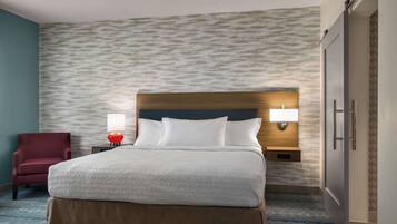 A hotel room with a bed, a nightstand, a lamp, a chair, and a wardrobe.
