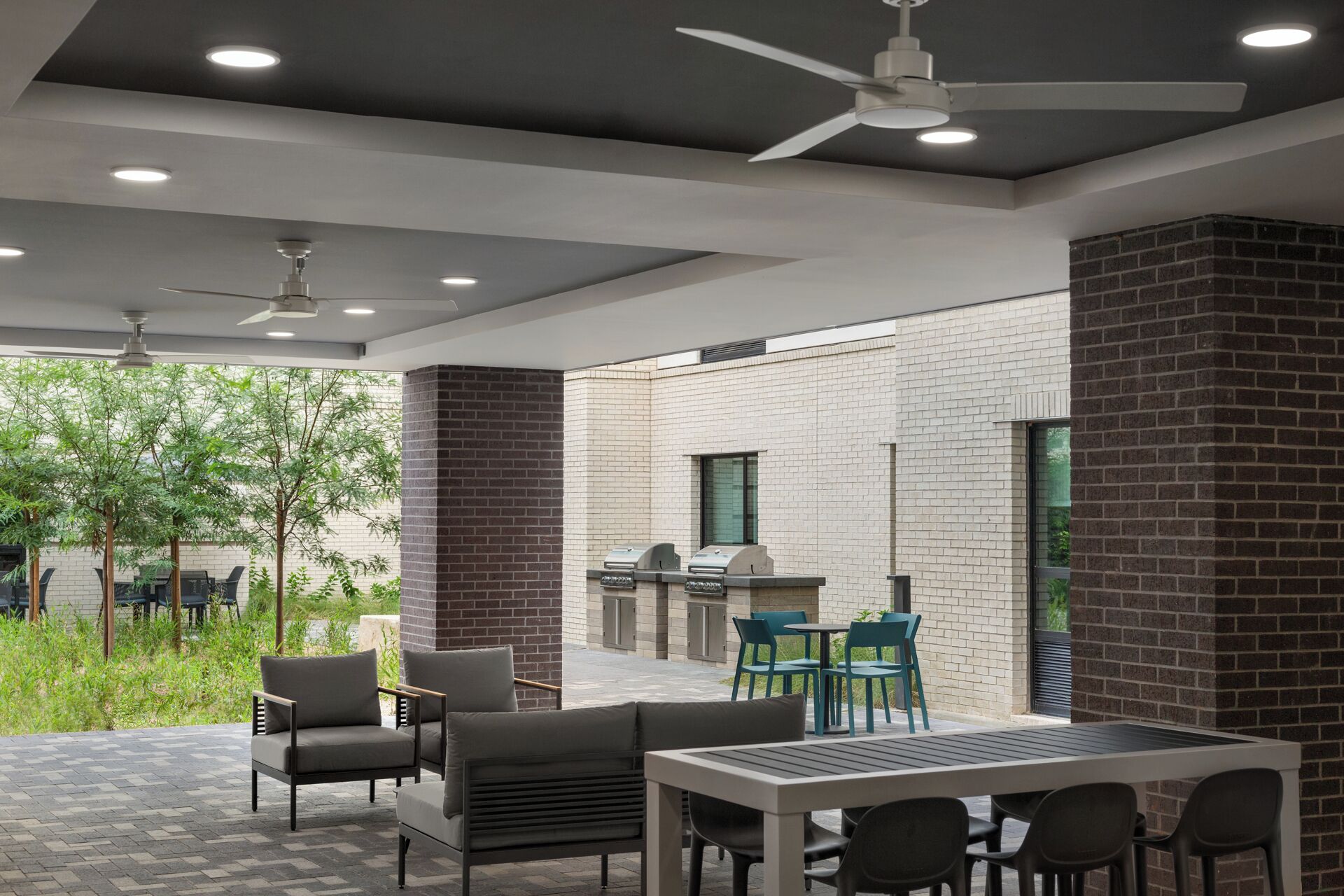 An outdoor patio area with seating, a grill, and a ceiling fan.