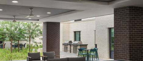 An outdoor patio area with seating, a grill, and a ceiling fan.