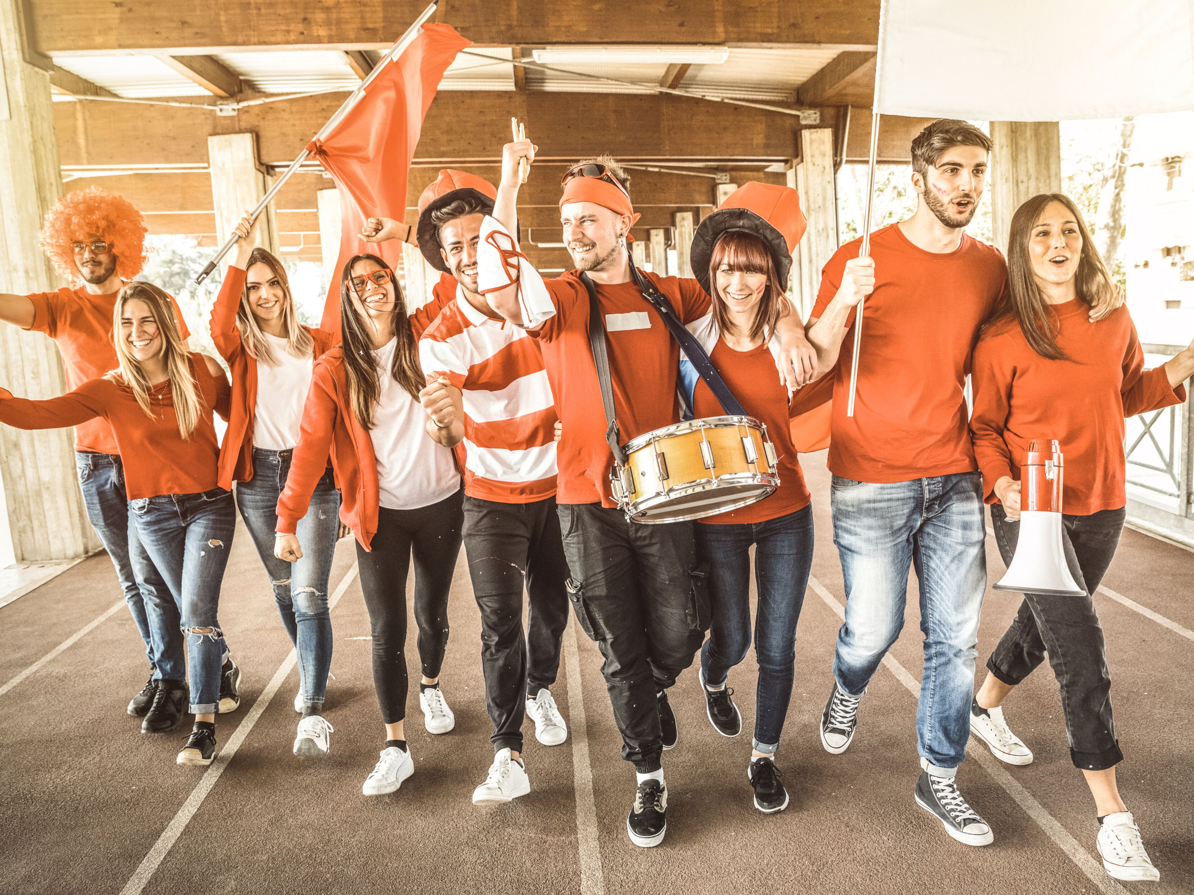 Een groep mensen in oranje kleding loopt over een betonvloer in een overdekte ruimte.