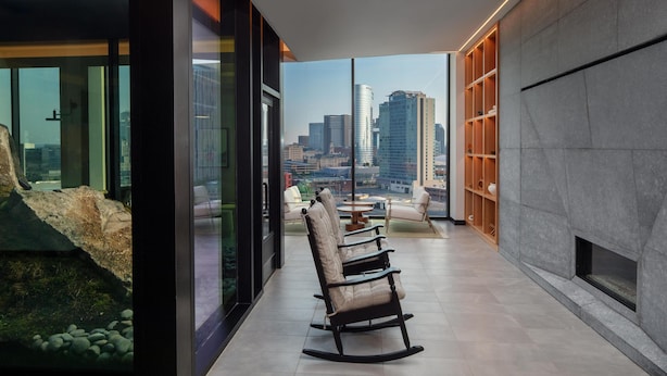 Um interior moderno com uma janela grande, uma lareira e uma área de estar com cadeiras.