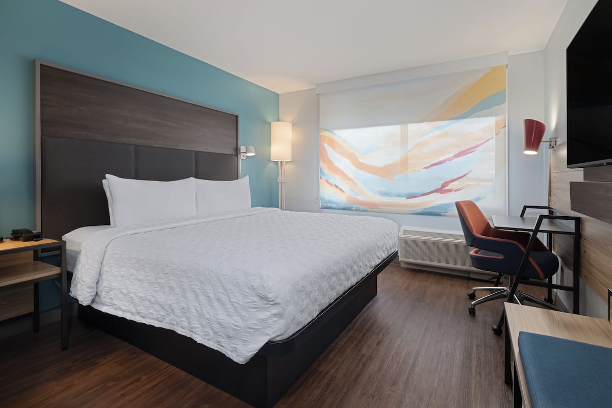 Une chambre d’hôtel moderne, dotée d’un grand lit, d’un bureau et d’une chaise.