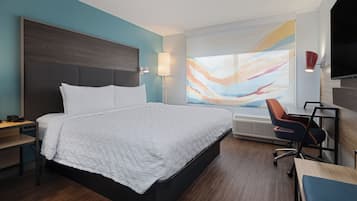 Una habitación de hotel moderna con una cama grande, un escritorio y una silla.