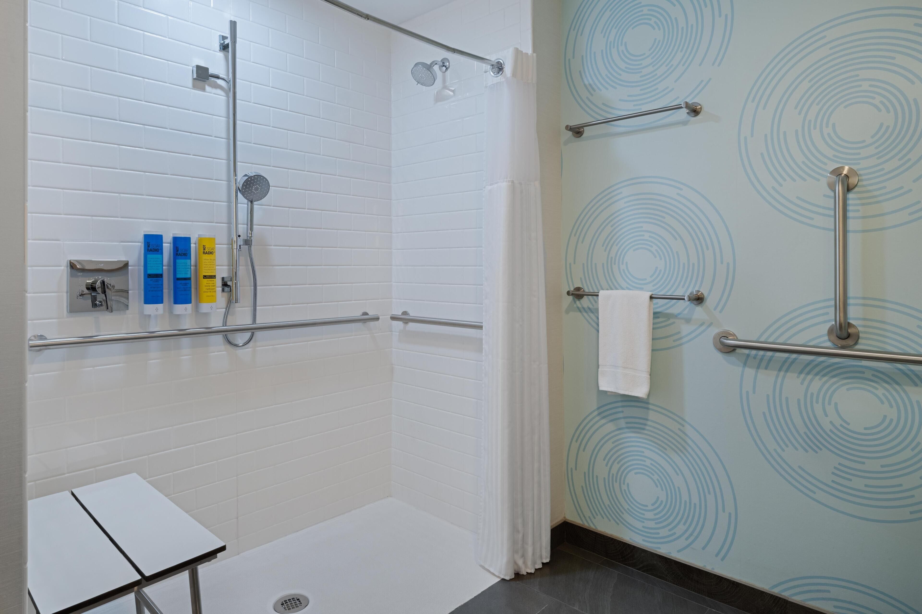 Une salle de bain moderne avec une douche, des toilettes séparées par une paroi en verre et un porte-serviettes.