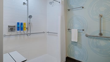 Une salle de bain moderne avec une douche, des toilettes séparées par une paroi en verre et un porte-serviettes.