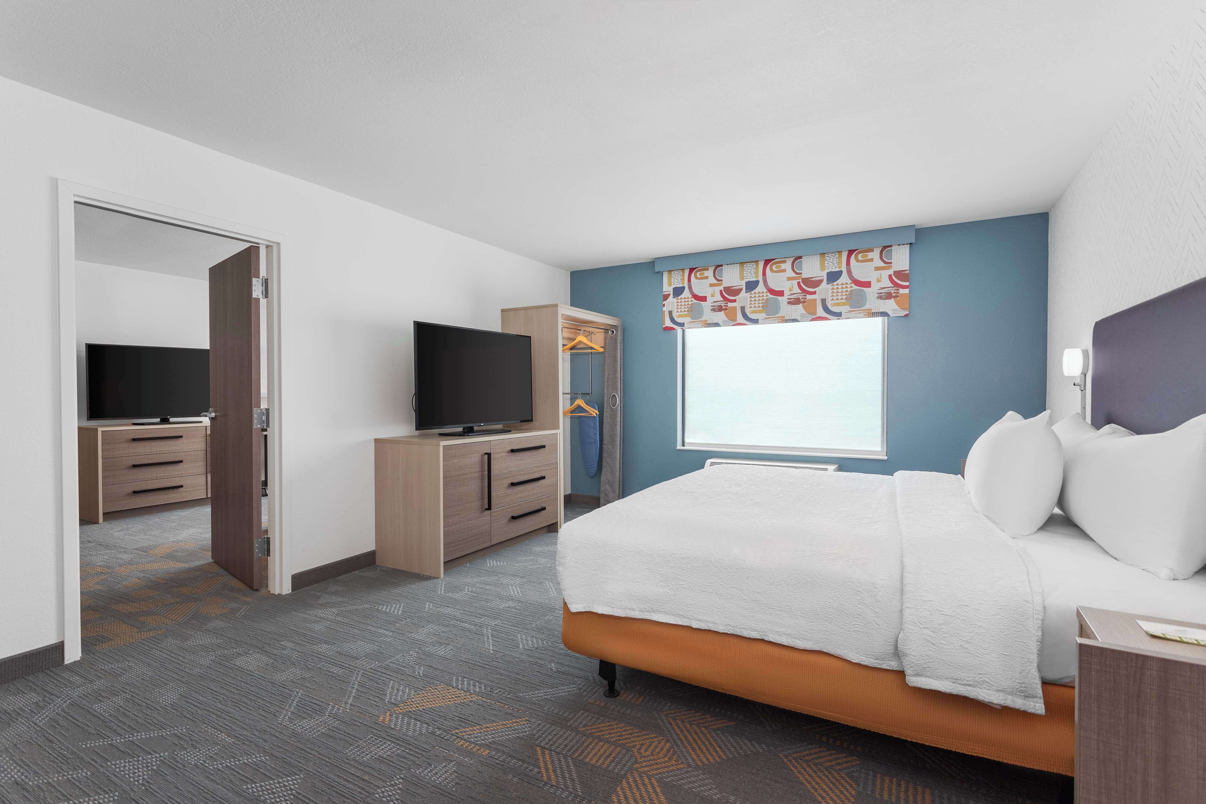 Une chambre d’hôtel avec un lit, une télévision, une armoire et une fenêtre avec un rideau.