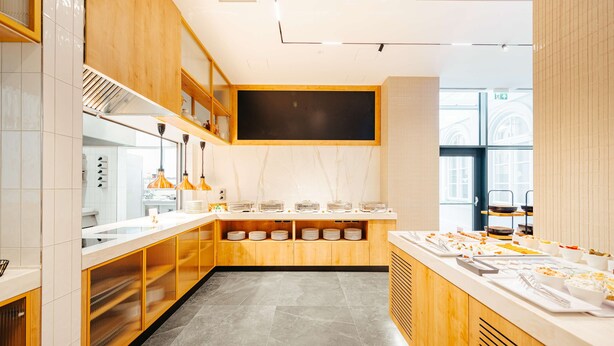 A modern kitchen with a long counter, wooden cabinets, and a large window.