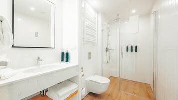 Un baño moderno con un lavamanos, espejo y retrete blancos.