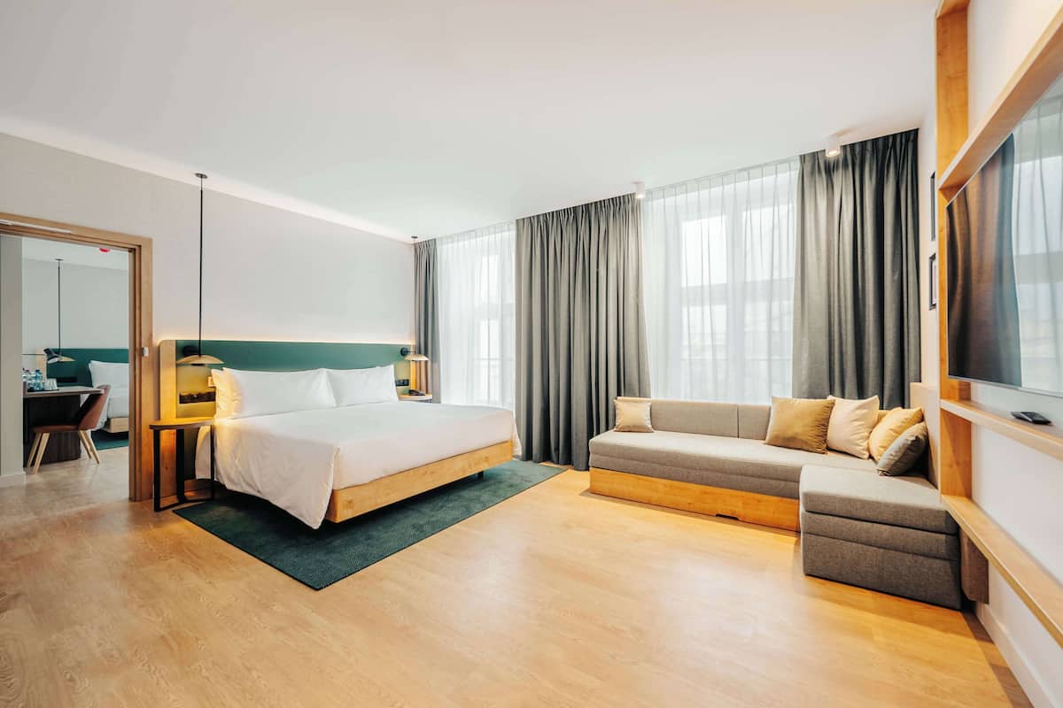 A modern hotel room with a bed, sofa, and desk.