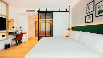 Une chambre d’hôtel comprenant un lit, un bureau, une chaise et une porte coulissante donnant accès à la salle de bain.