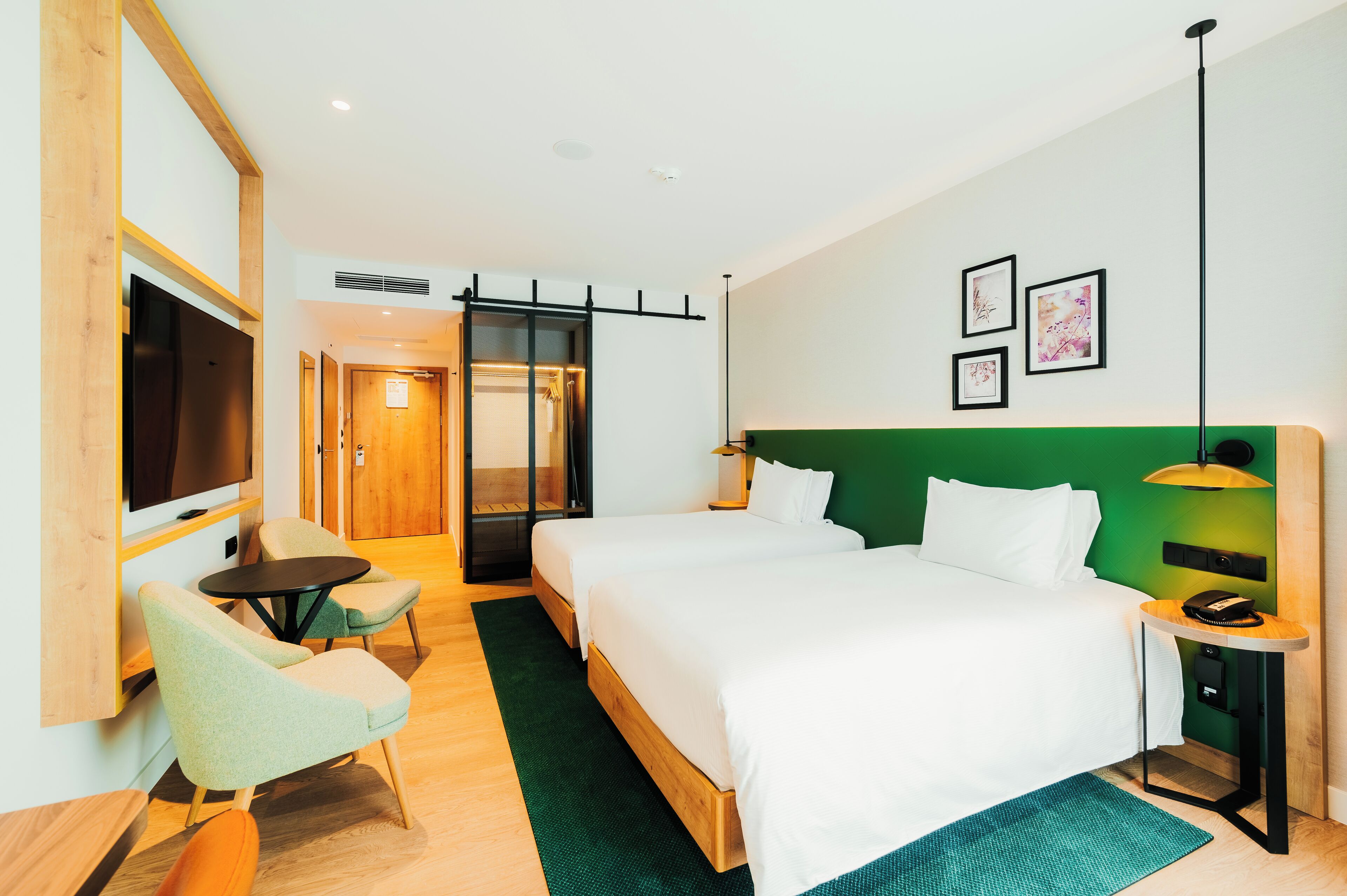 Quarto de hotel com uma cama grande, televisão, escrivaninha e cadeira.