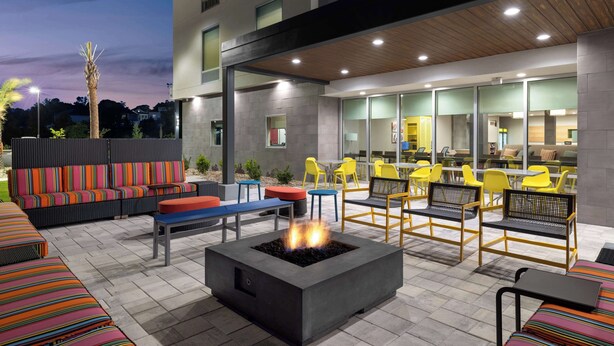 An outdoor seating area with a fire pit, colorful sofas, and yellow chairs. - Home2 Suites By Hilton Niceville Eglin Air Force Base (Niceville)