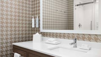 A modern bathroom with a houndstooth patterned wall, a white sink, a mirror, and a towel rack.