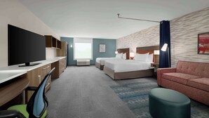 A hotel room with a desk, TV, two beds, a sofa, and a patterned rug. - Home2 Suites By Hilton Niceville Eglin Air Force Base (Niceville)