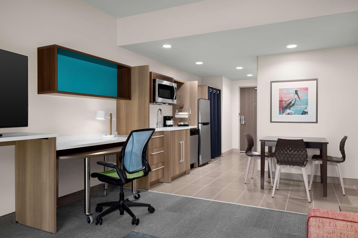 A modern kitchen with a microwave, refrigerator, and dining area with chairs and a table.
